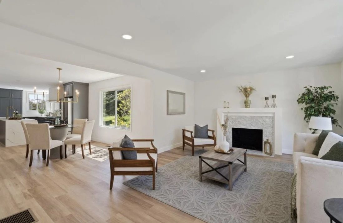 Open living and dining space with a fireplace and wood floors.