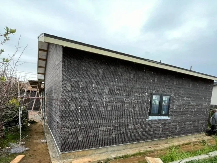 Detached ADU exterior with sheathing, a small window and sloped roof.