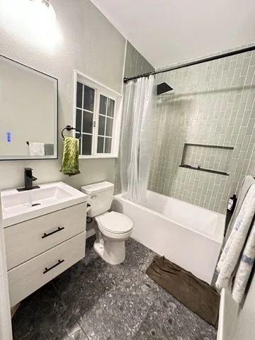 Bathroom with a white vanity and gray tiled bathtub surround.