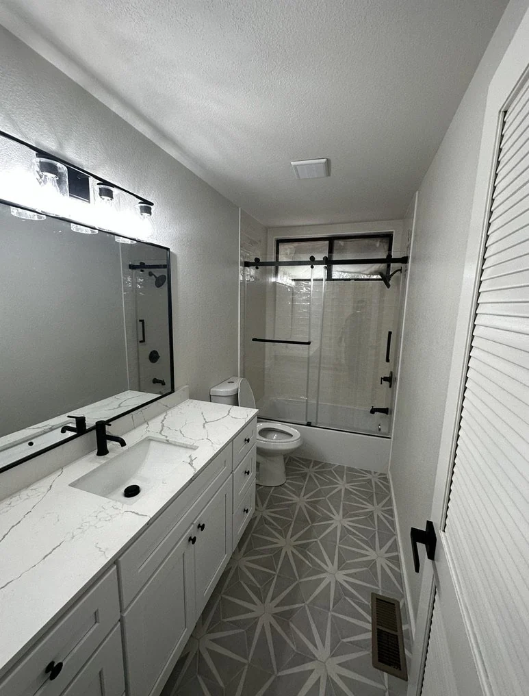 Bathroom with a long white vanity, dark tiled floor and glass shower screen.