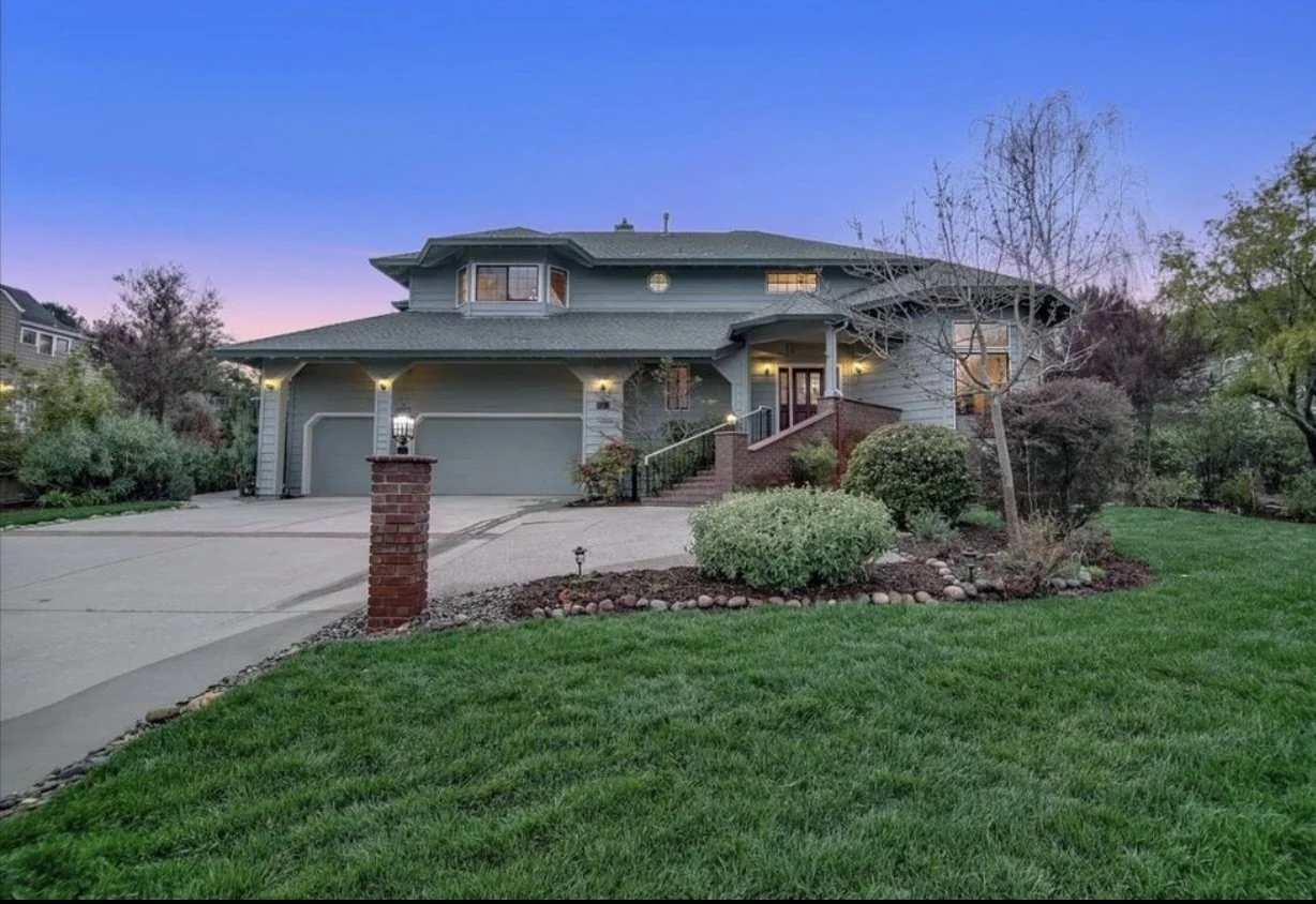 Two-story painted house with a driveway, garage and front landscaping.