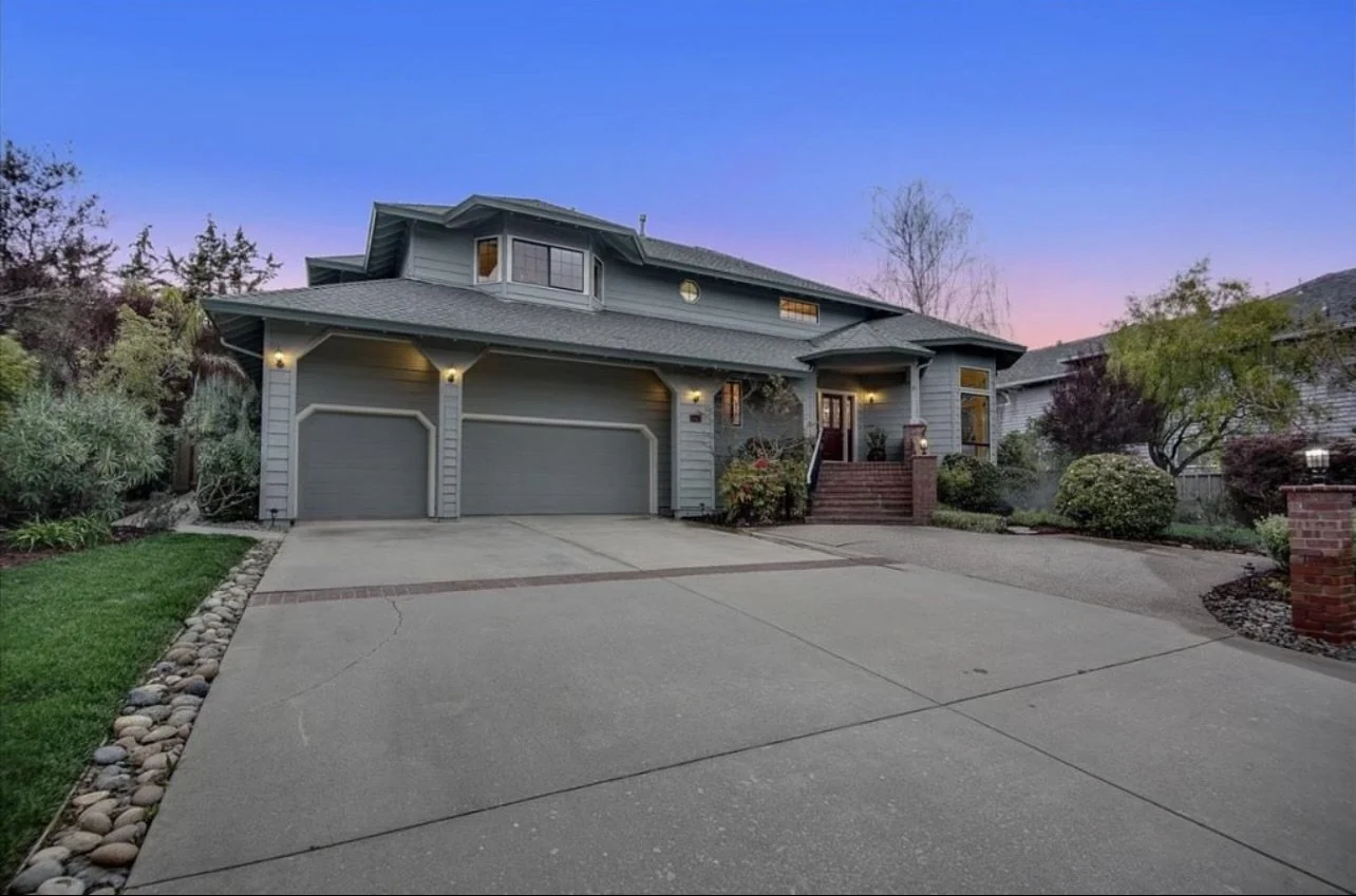 Two-story painted house and garage viewed from the driveway at dusk.