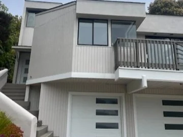 Painted house facade with upper windows and an exterior balcony.