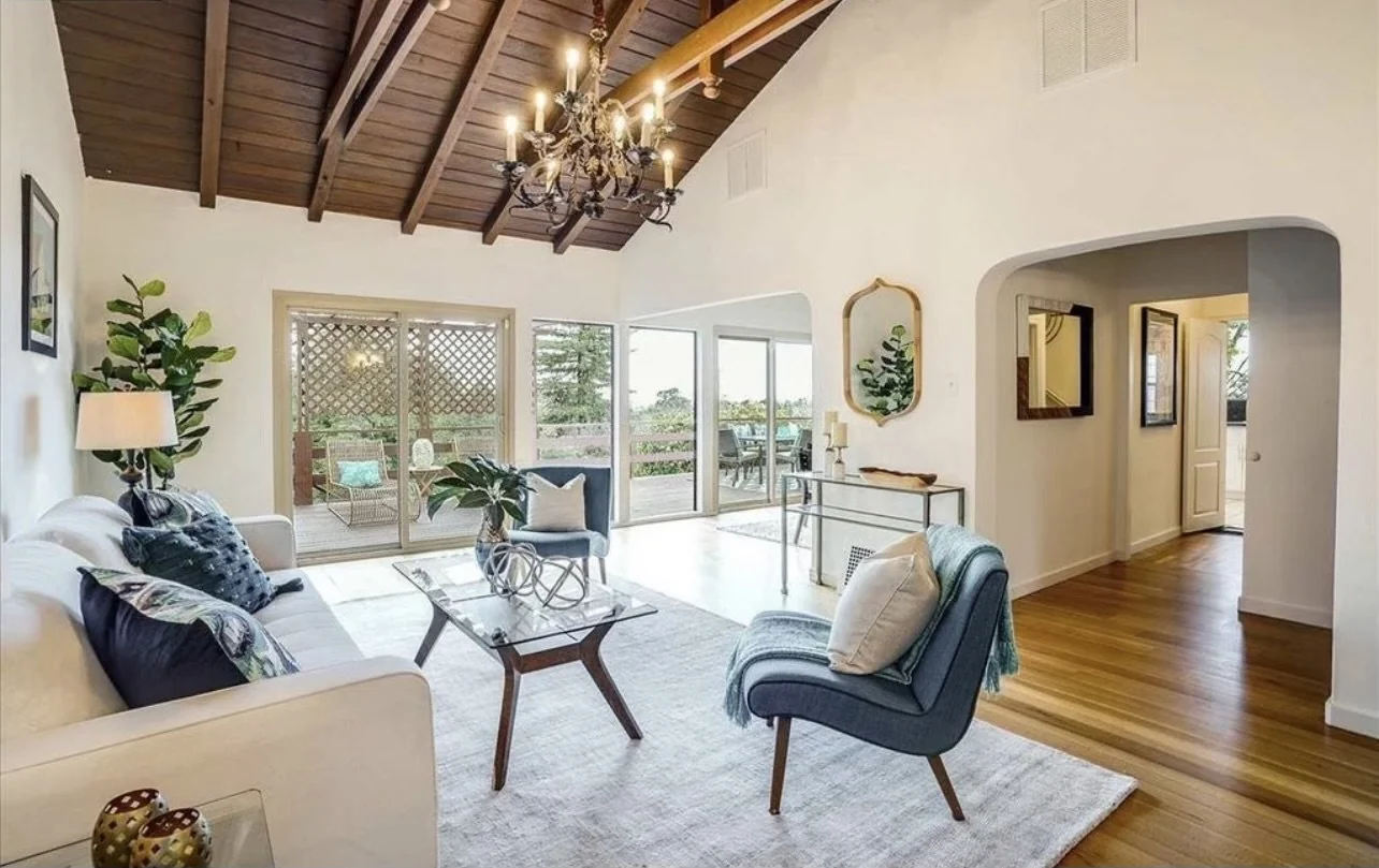 Living room with a wood ceiling, green seating and large garden windows.