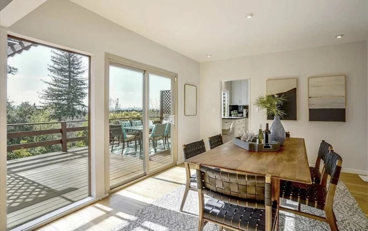 Dining area with pale walls and sliding doors to an outdoor deck.