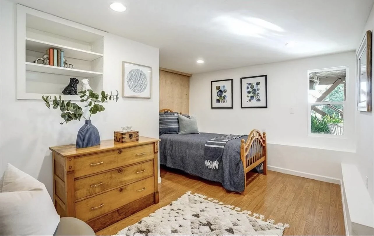 Interior room with pale walls, wood flooring, a dresser and a chair.