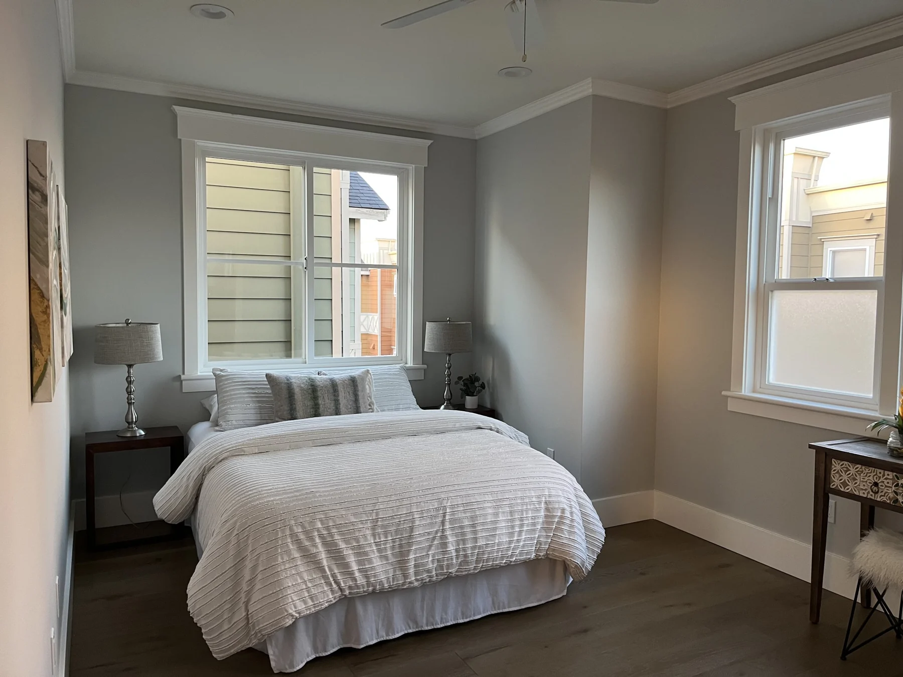 Bedroom with pale walls, a white bed and dark curtains.