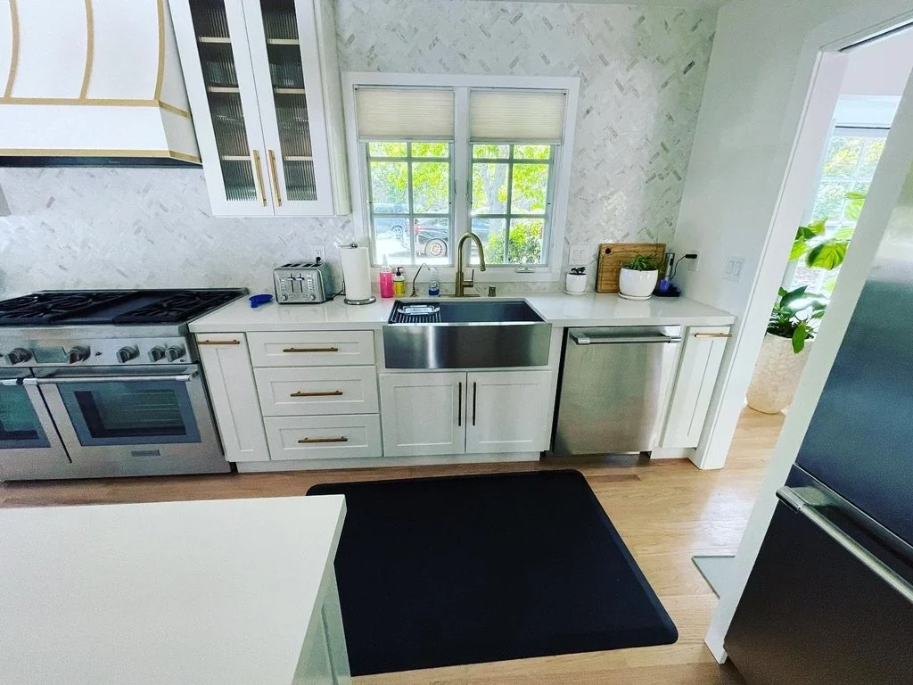 White kitchen corner with a window, sink and dark-topped island.