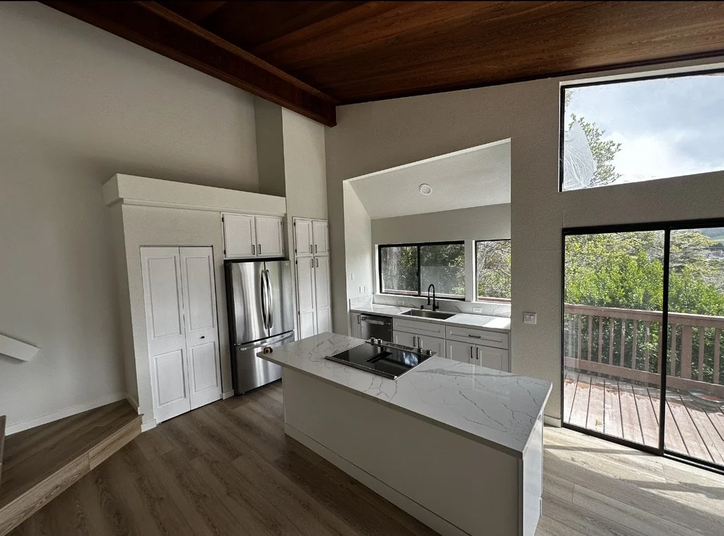 Kitchen with a wood ceiling, white cabinets and a garden-facing window.