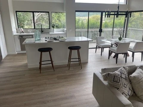 Open kitchen and dining area with island seating and large windows.