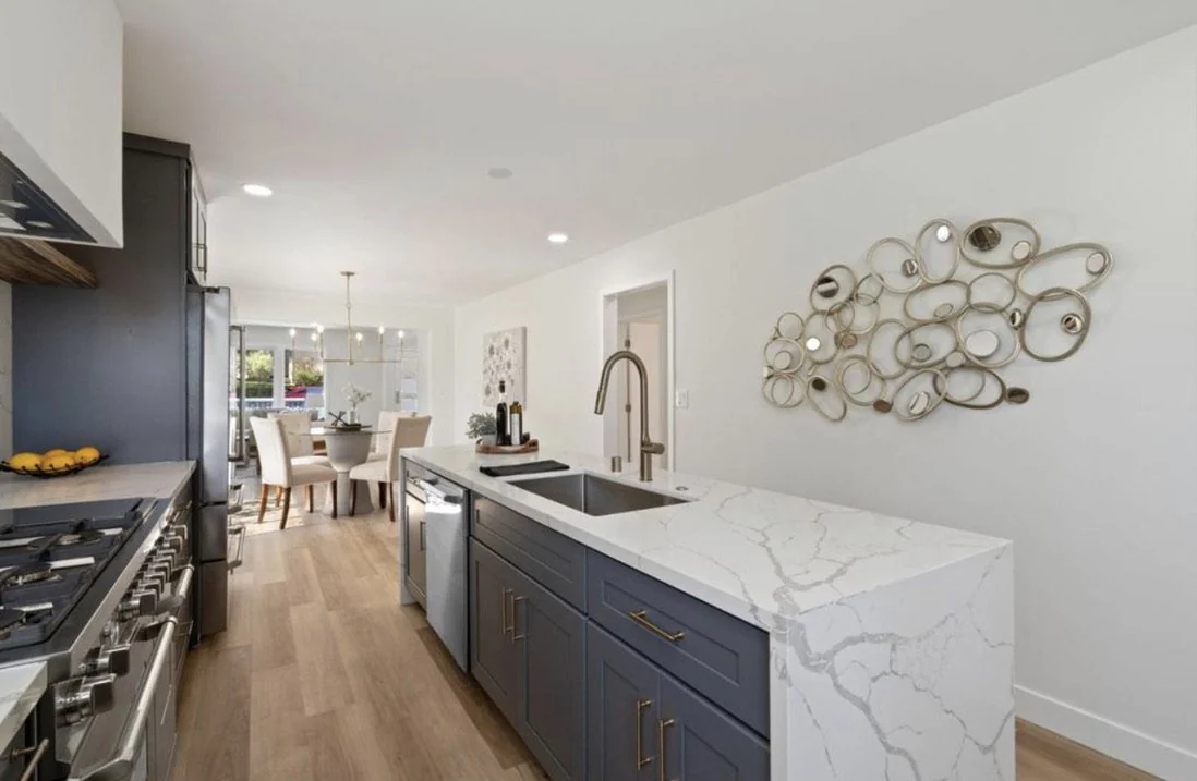 Marble kitchen island with charcoal cabinetry and a decorative wall mirror.