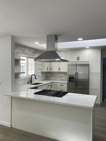 White kitchen viewed across a raised counter toward an open living area.